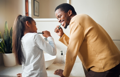 father and daughter brushing their teeth