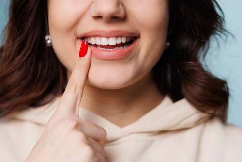 young woman pointing to her beautiful smile